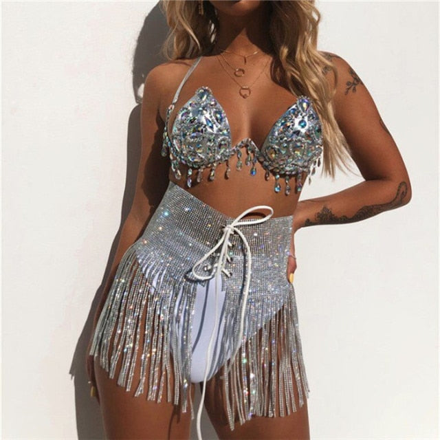 A woman wearing sparkly sequin bikini top and sprakly sequin skirt with tassel detail.
