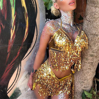 A rave girl wearing gold sequin fringe two piece set at a music festival.