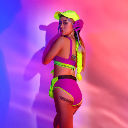 A woman wearing purple and neon green two piece set with wig hat for raves.