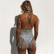 A woman wearing sparkly sequin backless bikini top and sprakly sequin skirt with tassel detail.